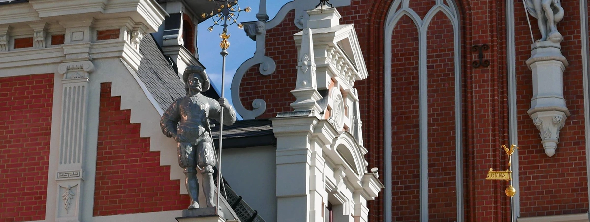 The image shows architectural details and a statue on the facade of the House of the Blackheads (Melngalvju nams) located in Riga, Latvia